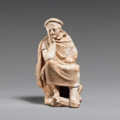 Terracotta statuette of a youth seated on a rock