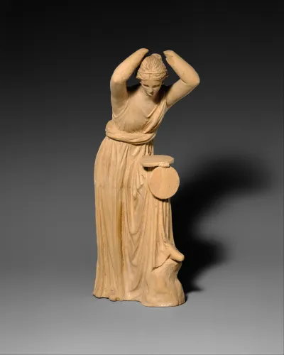 Terracotta statuette of a woman looking into a box mirror