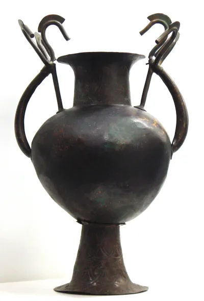 Bronzeurne mit Deckel (Deckelgefäβ, Blüte, Etruskisches Deckelgefäß mit zwei Henkeln, die oben in je drei Schwanen(?)hälse und Köpfe auslaufen, auf dem Deckel Knauf in Form einer sich aufschließenden Blume)