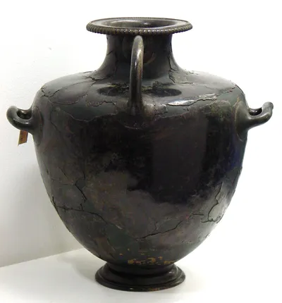 Hydria, aus Fragmenten mittels Nieten auf einer Unterlage zusammengesetzt. Auf dem Mündungsrand die eingeschlagene griechische Inschrift: ΑΘΛΟΝ ΕΓ ΛΑΜΨΑΚΟ ΕΠΙ ΛΕΩΦΑΝΤΟ ΤΟ ΛΑΜΠΡΟ