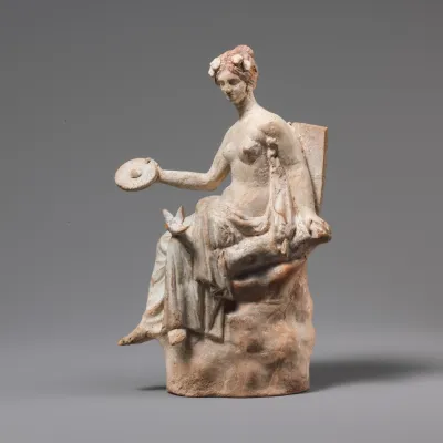 Terracotta statuette of Aphrodite seated on a rock