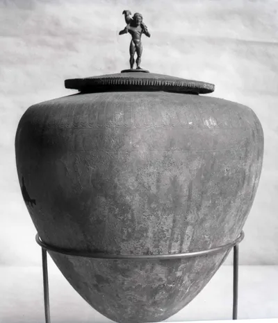 Deckelgefäβ ("Deckelgefäß mit eingeritzten Ornamenten und Figurenfries" ..."auf dem Deckel die Figur eine widdertragenden Hermes" (Urne mit Statuette eines Widderträgers auf dem Deckel))