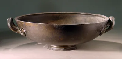 Zweihenkliges römisches Becken; die Henkel enden in Greifenköpfen; Wandung an einigen Stellen zerstört