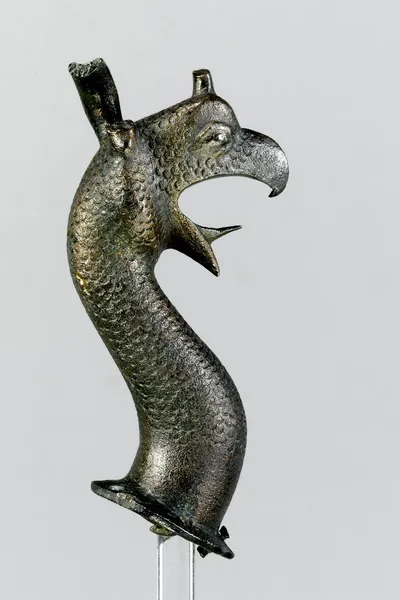 Greifenprotome, gegossen, wohl zu Inv. Sa. 89 gehörig, reduziert, Gussfehler am Hals unten, linkes Ohr stark nach innen gebogen, rechtes verloren, Kernmasse und Kernstützen erhalten